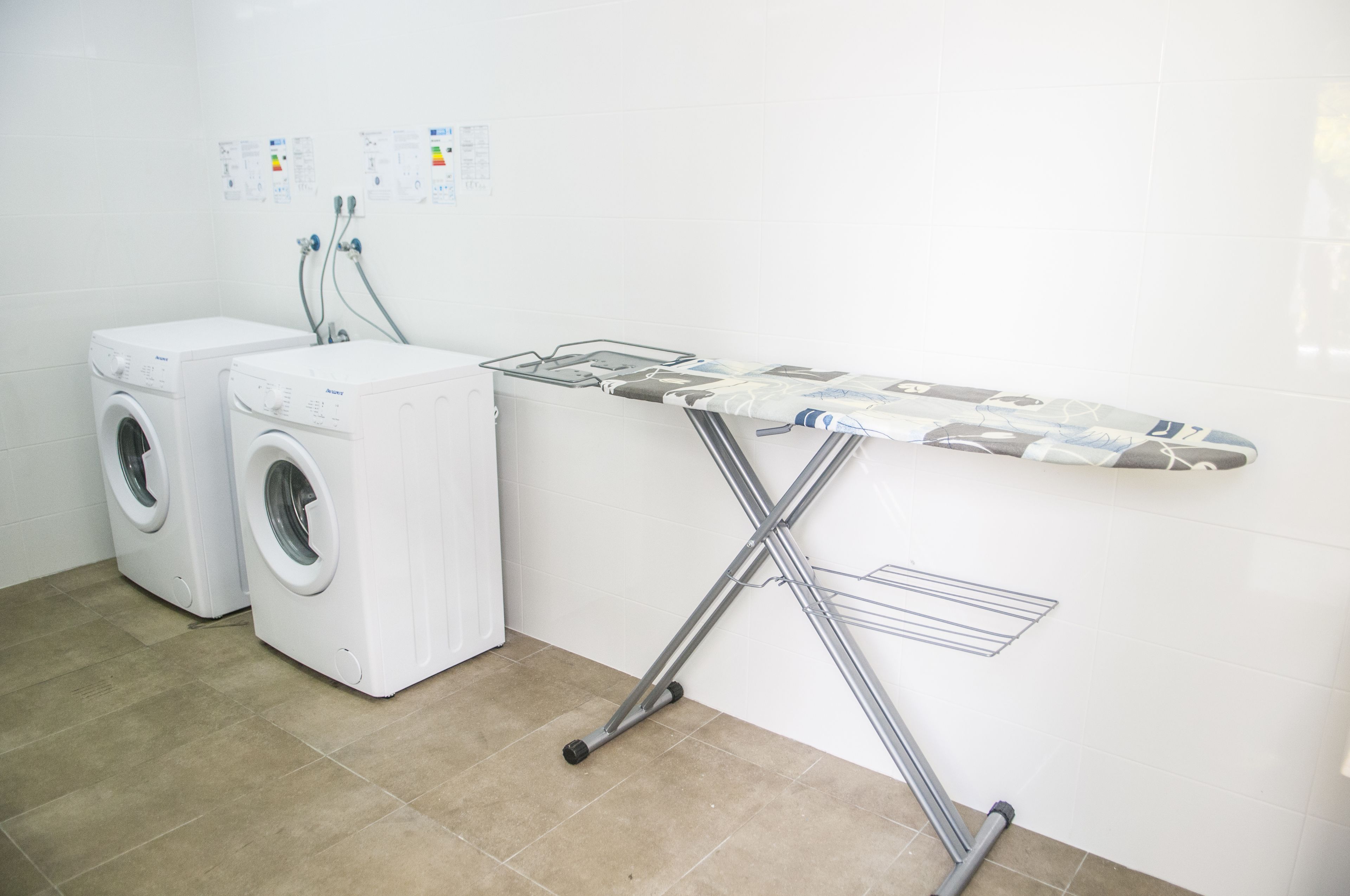 A laundry area with two washing machines and an ironing board.