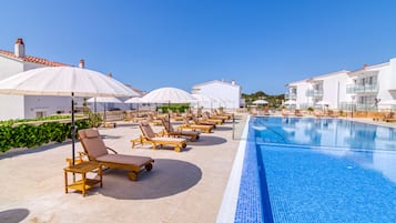 Una piscina al aire libre, sombrillas, tumbonas