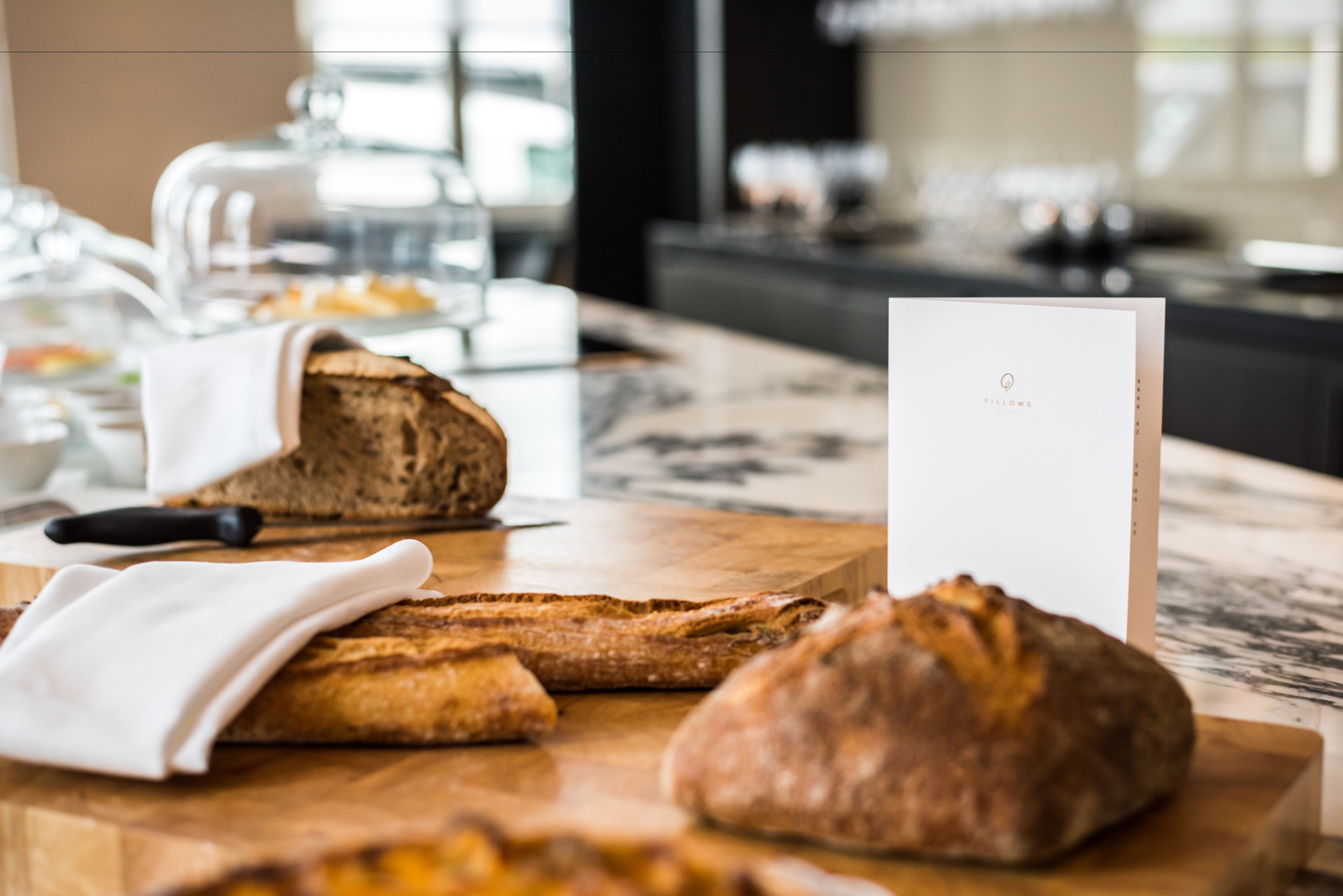 A wooden table with a loaf of bread, a knife, and a napkin.