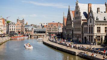A riverside promenade with historic buildings, a boat, and people enjoying the view.