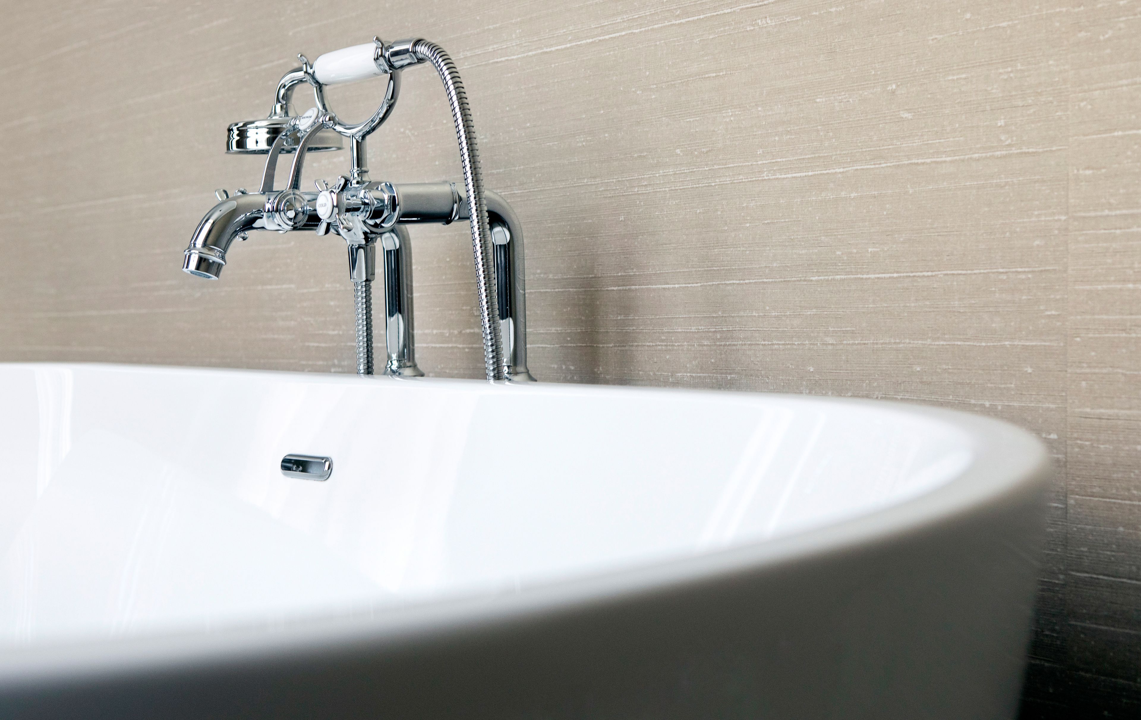 A white bathroom sink with a chrome faucet and a handheld showerhead.