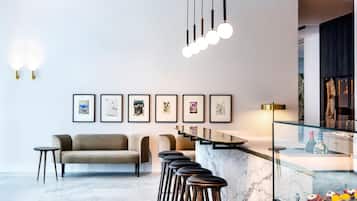 A modern bar area with a marble countertop, bar stools, and framed artwork on the wall.