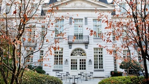 A white building with a symmetrical facade, large windows, and a central entrance with a decorative arch.