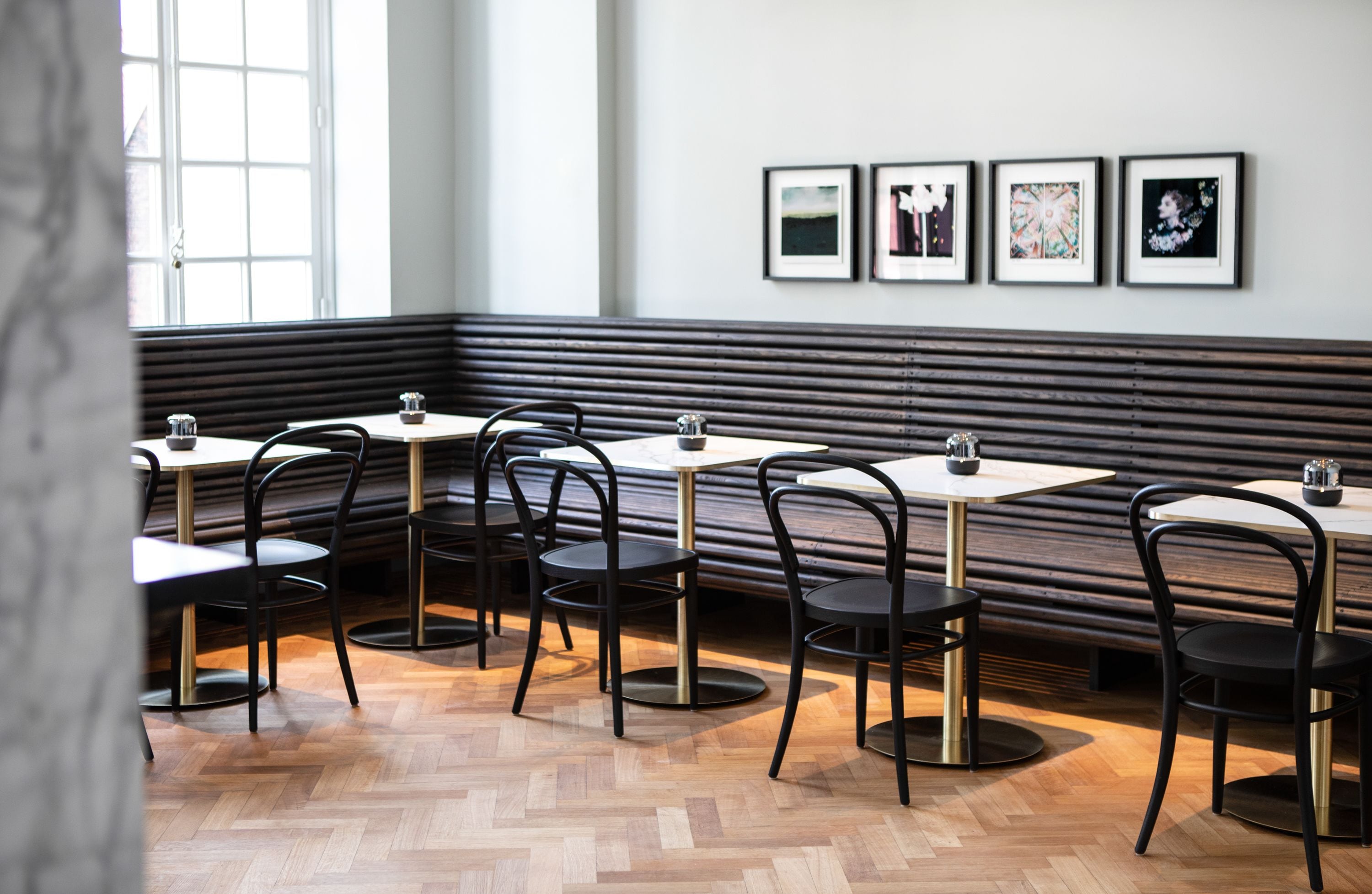 Ein Restaurant mit Holzbänken und -tischen, gerahmten Bildern an der Wand und einem Zargenholzboden.