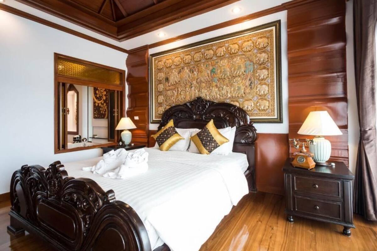 Een ruime slaapkamer met een groot bed, een versierd hoofdeinde en een groot decoratief schilderij erboven.