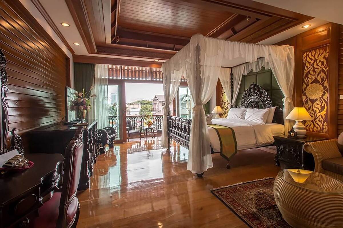 Een slaapkamer met hemelbed, houten meubels, een balkon met uitzicht en een klassiek ontwerp.