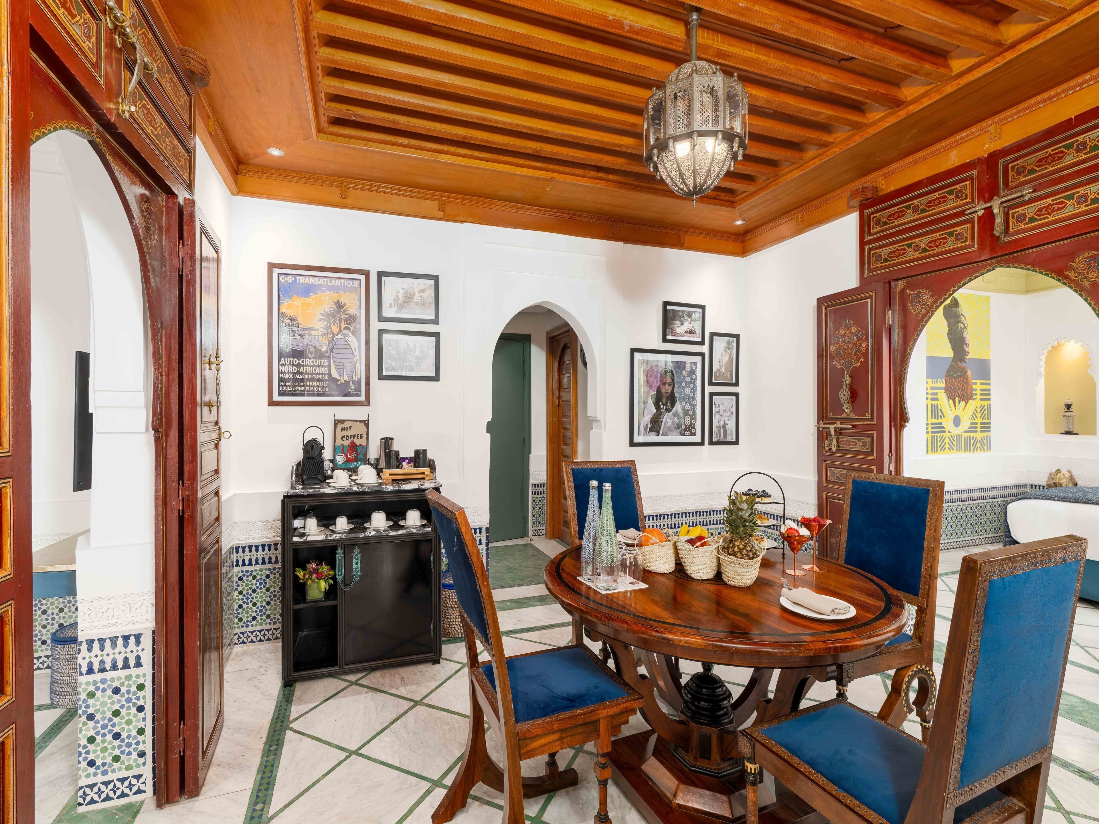 A dining area with a round wooden table, blue upholstered chairs, and a chandelier.
