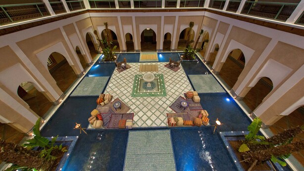 A spacious indoor pool area with multiple seating arrangements and a central decorative element.