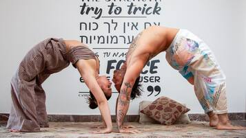 Two people performing a yoga pose in a room with a motivational quote on the wall.