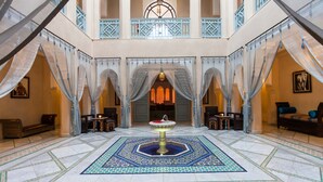 A spacious lobby with a central fountain, ornate arches, and a patterned floor.