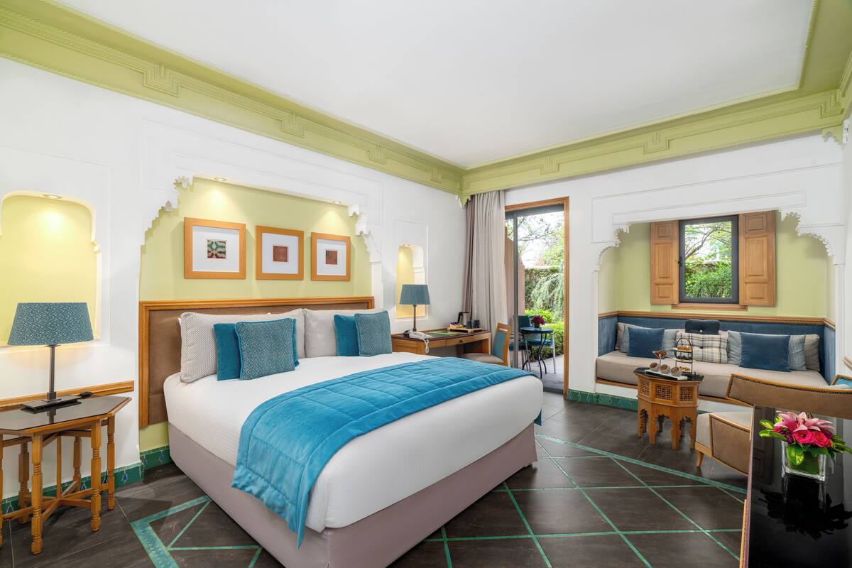 Une chambre d’hôtel avec un grand lit, un bureau avec une lampe, un canapé et une table à manger.