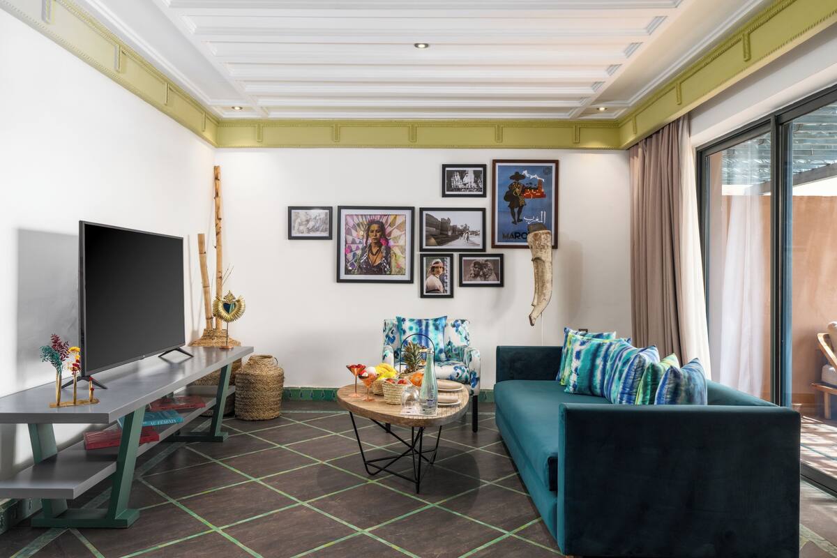 Un salon moderne avec un téléviseur à écran plat, un canapé, une table basse et des œuvres d’art accrochées aux murs.