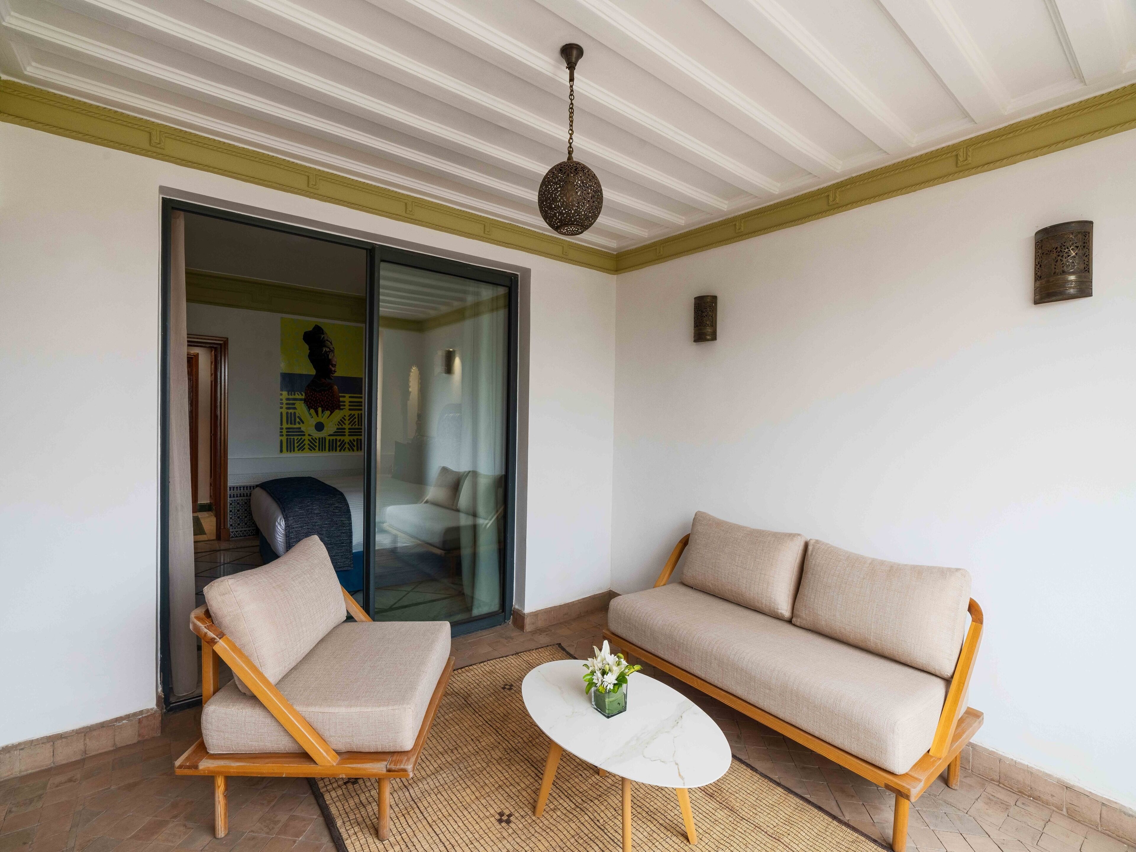 A modern living room with a sofa, two armchairs, a coffee table, and a glass door leading to another room.