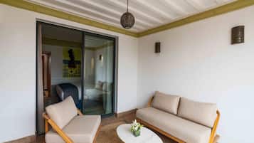 A modern living room with a sofa, two armchairs, a coffee table, and a glass door leading to another room.