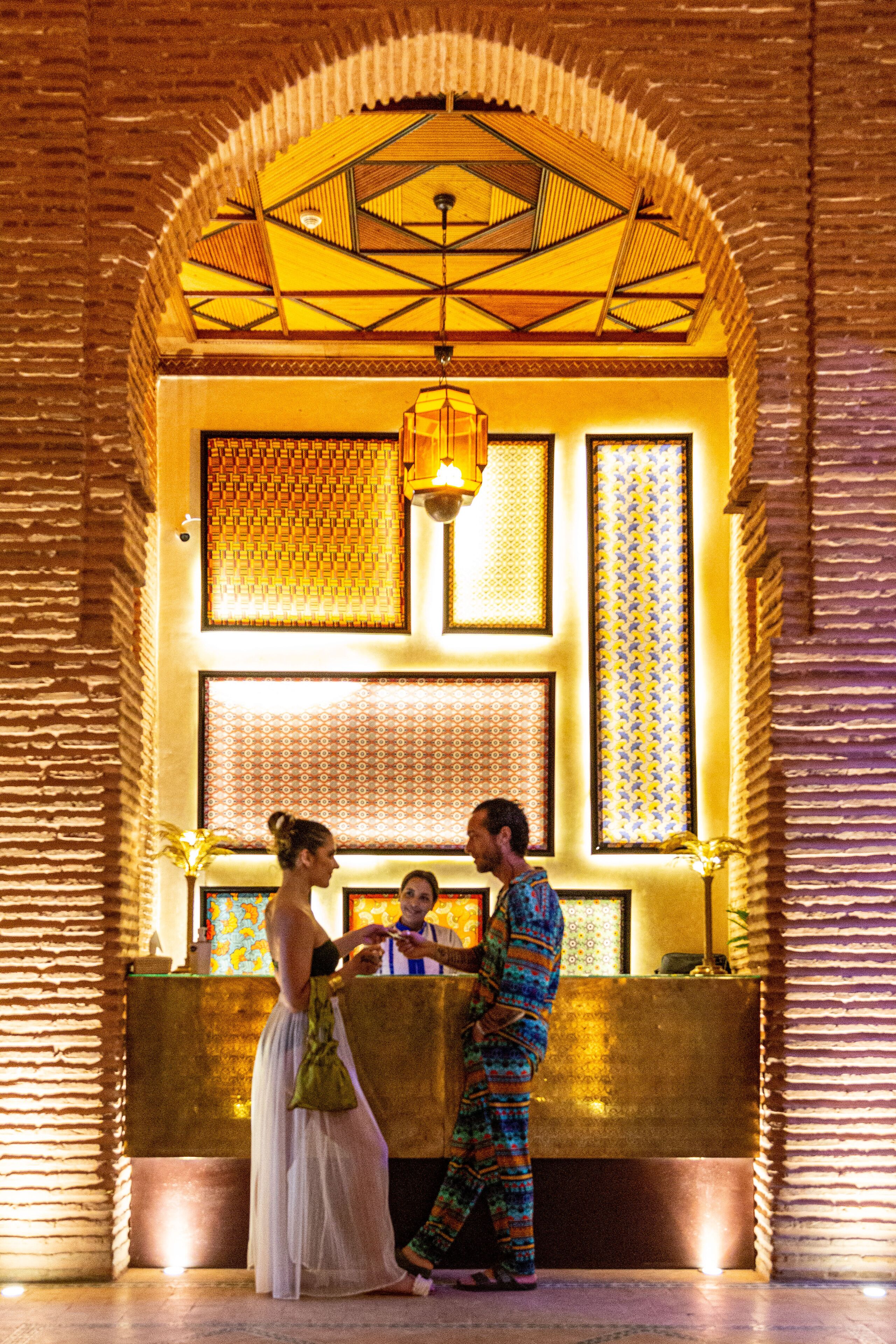 A reception area with a check-in counter, a patterned wall, and a ceiling with geometric designs.