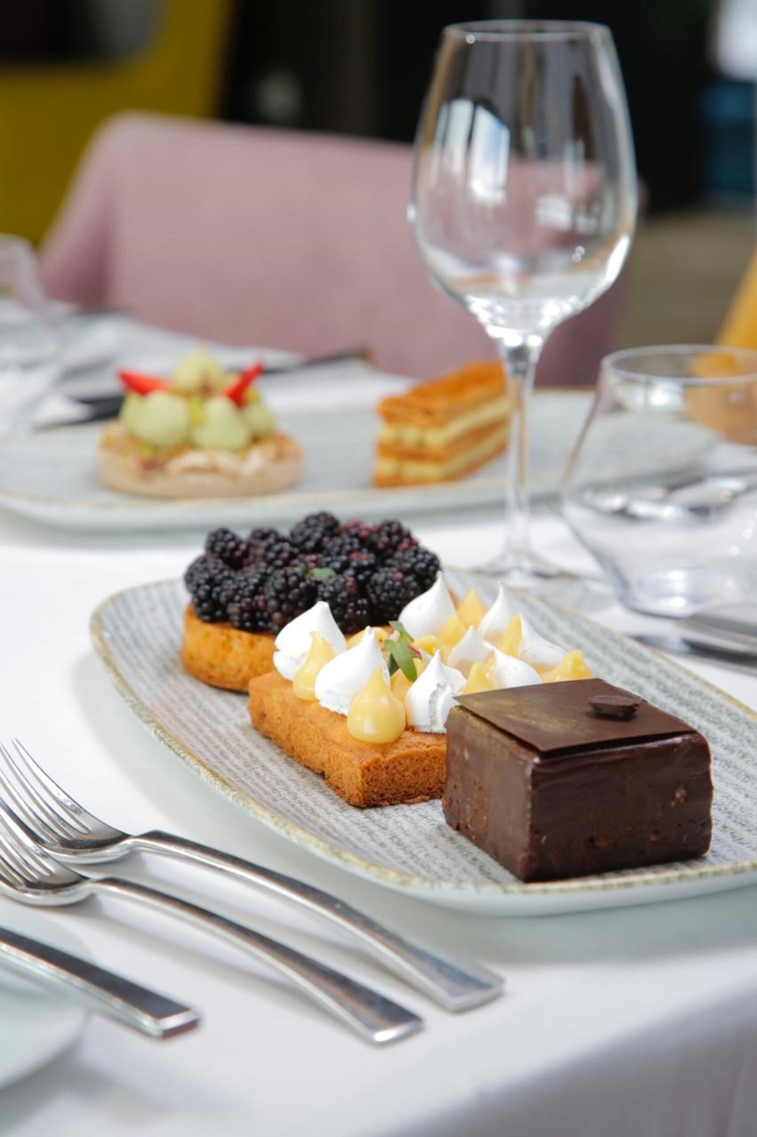 A dessert plate with various sweets and a wine glass.