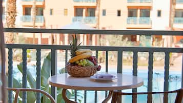 Un balcone con un tavolo apparecchiato per due, con un cesto di frutta e un tovagliolo piegato.