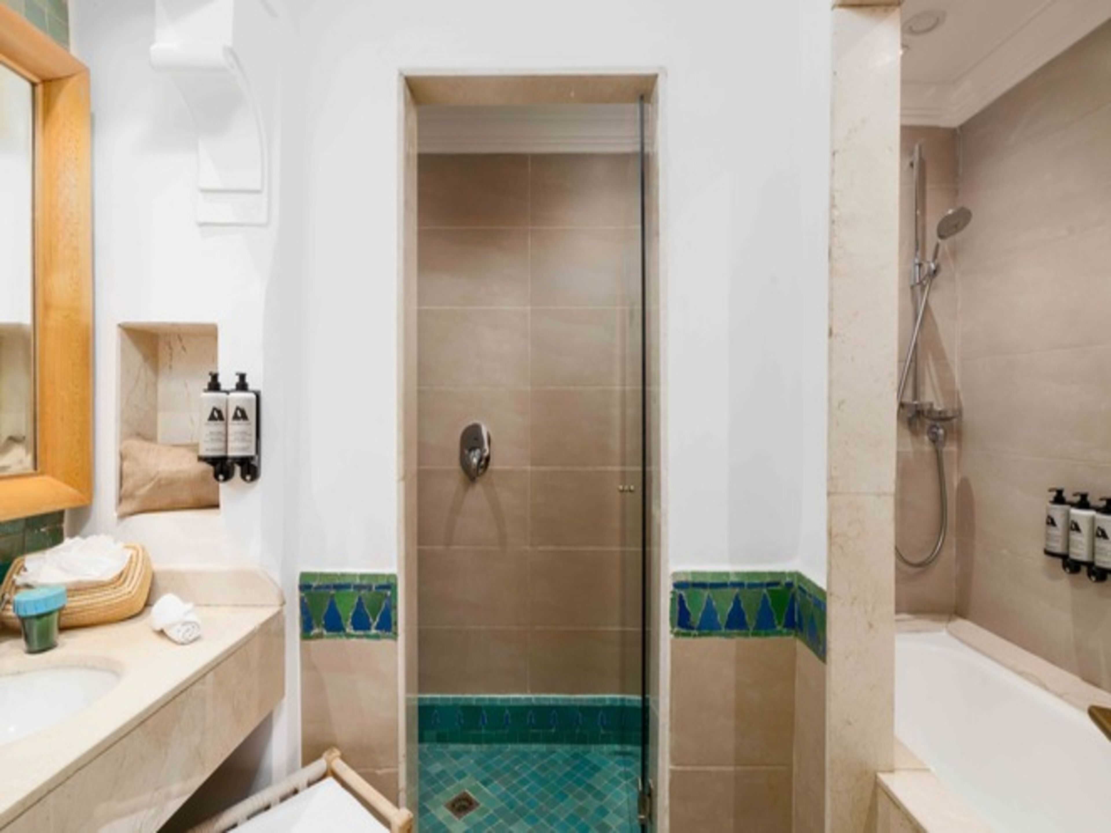 Un bagno con doccia, lavandino e specchio. Prodotti da bagno a parete e asciugamano sul ripiano.