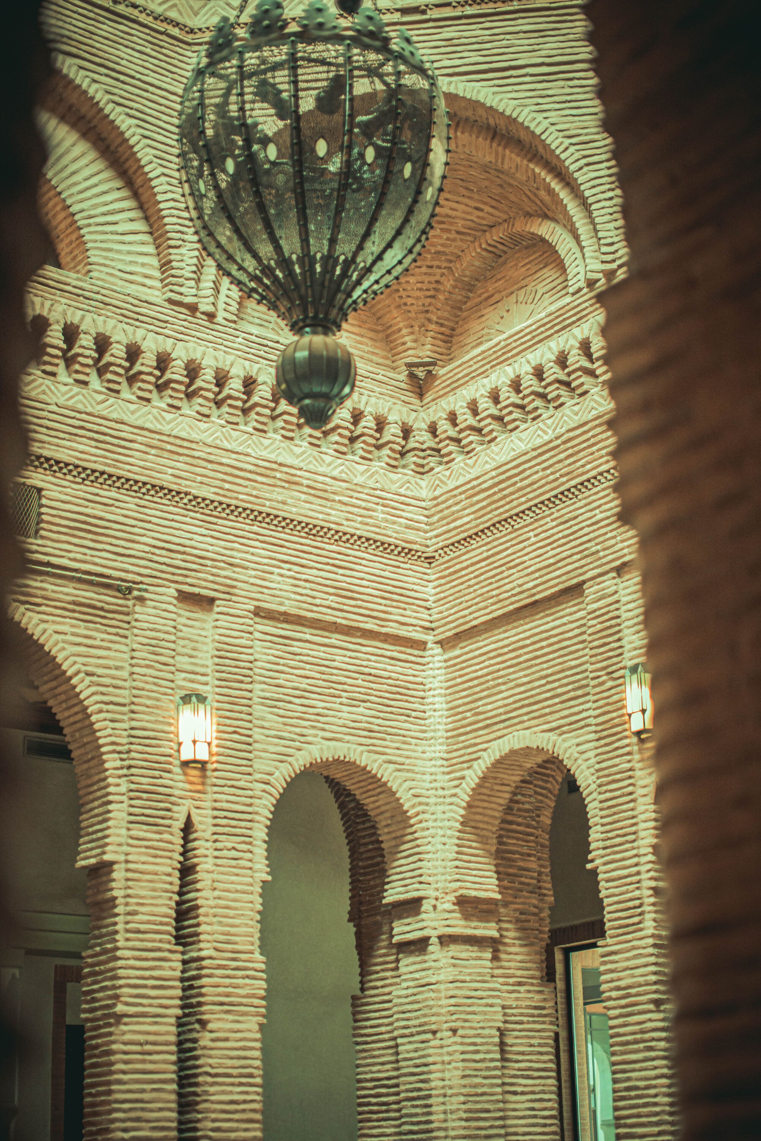 A detailed view of a building's interior with a large, ornate chandelier and multiple arched doorways.