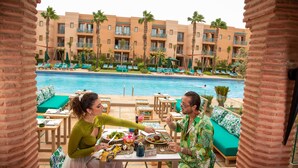 A poolside dining area with a view of the pool and hotel buildings.