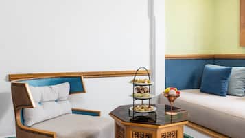 A room with a sofa, a chair, a small table with a tray of snacks, and a decorative bowl.