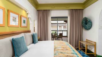A hotel room with a large bed, a wooden headboard, a small table, and a view of the outside balcony.