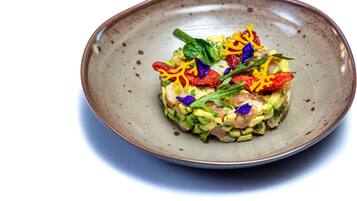 A dish on a ceramic plate with garnishes.