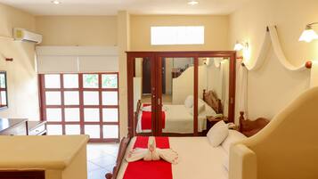 A hotel room with a bed, a desk, a wardrobe, and a bathroom visible through a glass door.