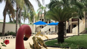 Un resort con zona de piscina, palmeras y un edificio de techo verde.