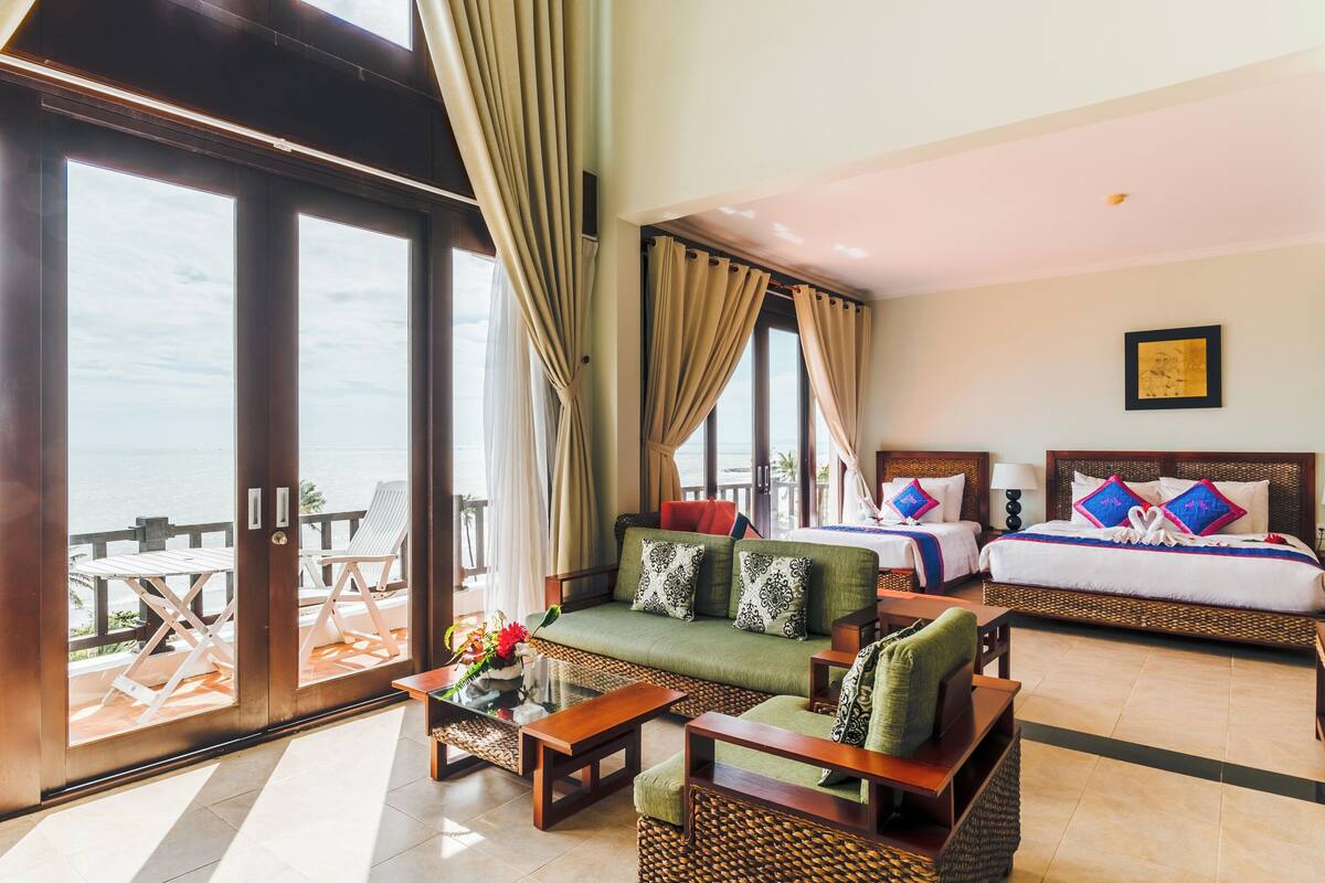 A hotel room with a balcony, a sofa, a bed, and a dining table.