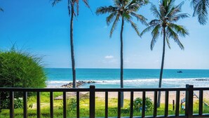 A beach view with palm trees, ocean, and a wooden fence. - Lotus Muine Resort & Spa (Phu Thuy)