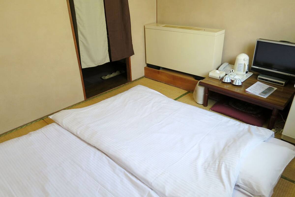 Une chambre d’hôtel équipée d’un lit, d’un bureau avec un ordinateur, d’un téléphone et d’une machine à café.