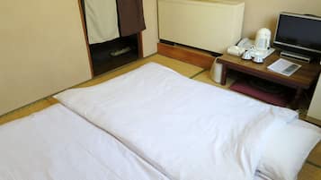 A hotel room with a bed, a desk with a computer, a telephone, and a coffee maker.