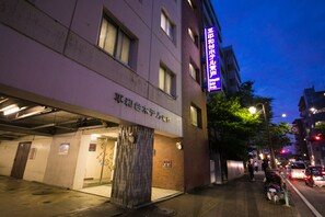 Een gebouw met een bord waarop hotel staat aangegeven. Er zijn meerdere ramen en een duidelijke ingang.
