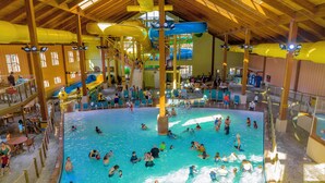 An indoor swimming pool with multiple lanes, slides, and a seating area with tables and chairs. - Grand Country Waterpark Resort (Branson)
