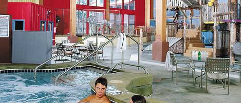 Ett område med ett bubbelbad, en pool, träbjälkar och en röd vägg.