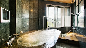 Ein modernes Badezimmer mit einer großen Badewanne, Holzboden und einer Duschkabine aus Glas.