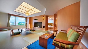 Ein modernes Wohnzimmer mit Tatami-Matten, einem Holztisch, einer Couch und einem Fernseher.
