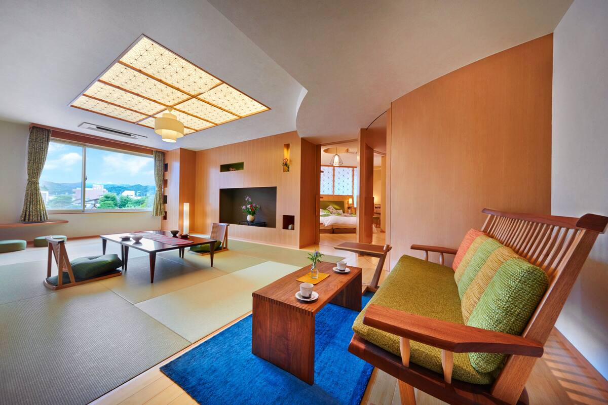 A modern living room with tatami mats, a wooden coffee table, a sofa, and a television.