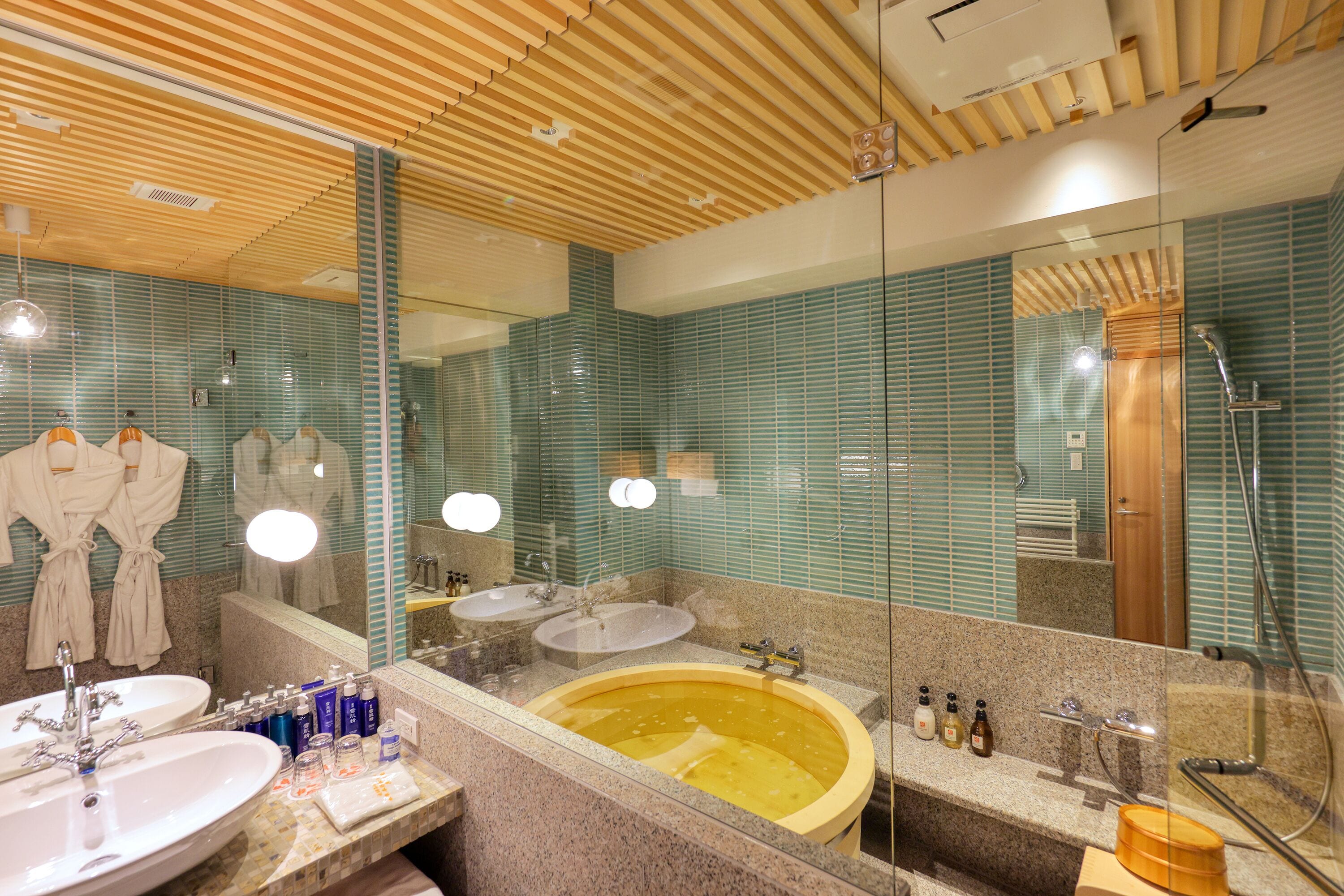 A bathroom with two sinks, a bathtub, and a shower. There are towels and toiletries on the counter.
