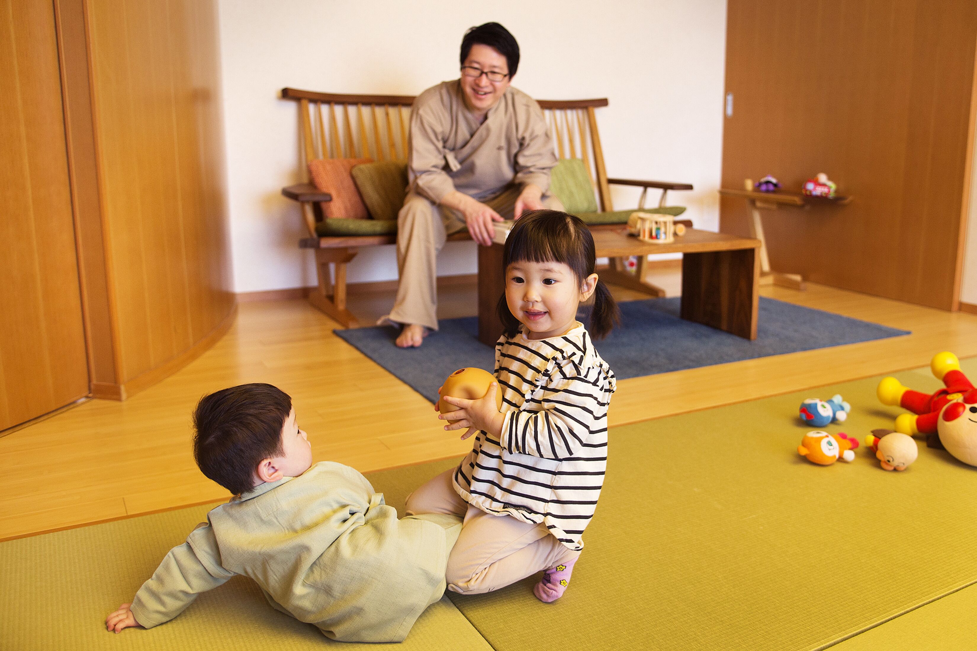 A room with a tatami mat floor, a wooden sofa, and a small table with toys.