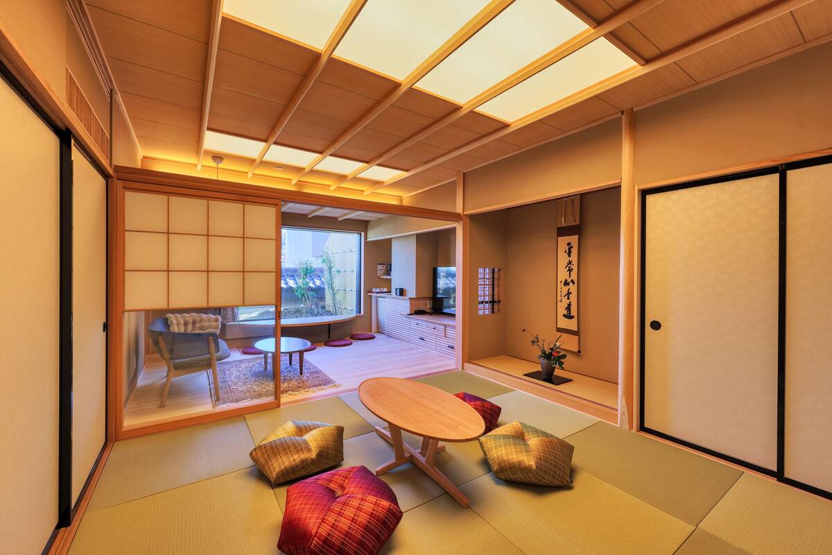 Ein traditioneller japanischer Raum mit Tatami-Bodenbelag, einem niedrigen Tisch und Kissen.