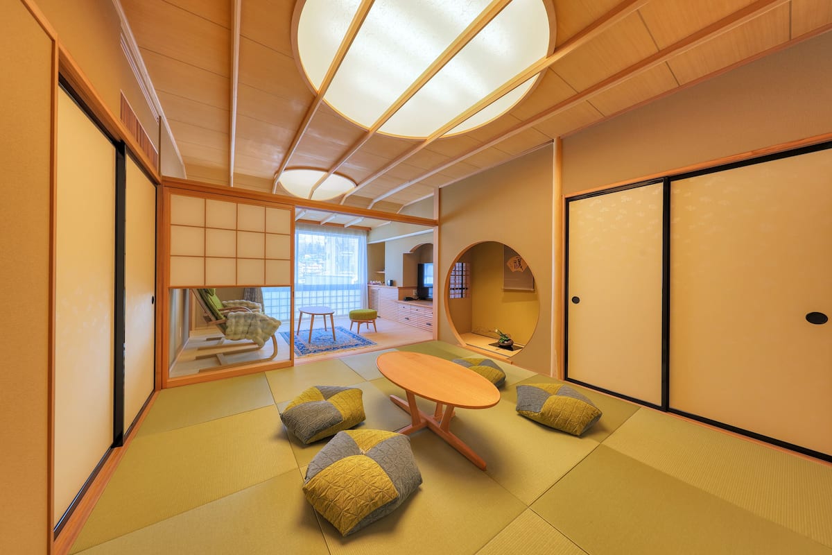 A traditional Japanese room with tatami flooring, a low table, cushions, and sliding doors.