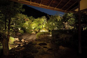 Un jardin bien éclairé, avec un chemin de pierres, entouré d’arbres et de rochers.