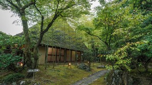 Un edificio japonés tradicional rodeado de vegetación exuberante y un sendero de piedra.