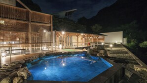 Une piscine avec une terrasse en bois et un bâtiment en arrière-plan.