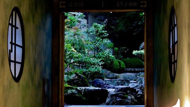 Une pièce de style japonais traditionnel, avec un sol recouvert de tatamis, une porte coulissante en papier de riz (shoji) et une vue sur un jardin luxuriant.