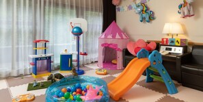 Un salón de juegos para niños con una piscina de pelotas, un tobogán, una tienda de campaña y varios juguetes.
