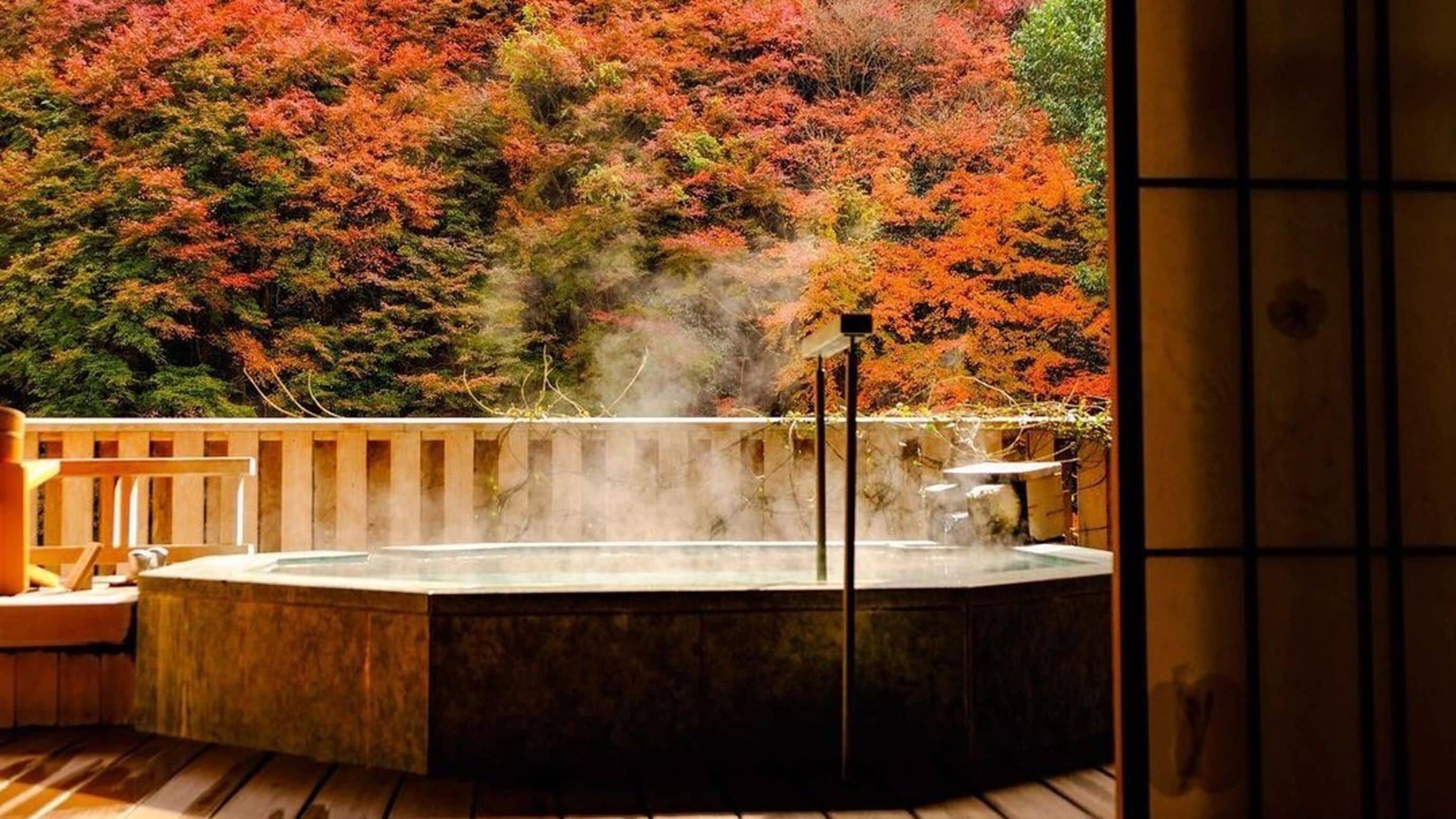 A hot tub with a wooden deck and a view of autumn foliage.