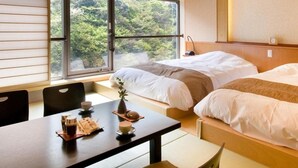 Une chambre d’hôtel avec deux lits, une table à manger avec des tasses à café, et une vue sur la verdure par la fenêtre.